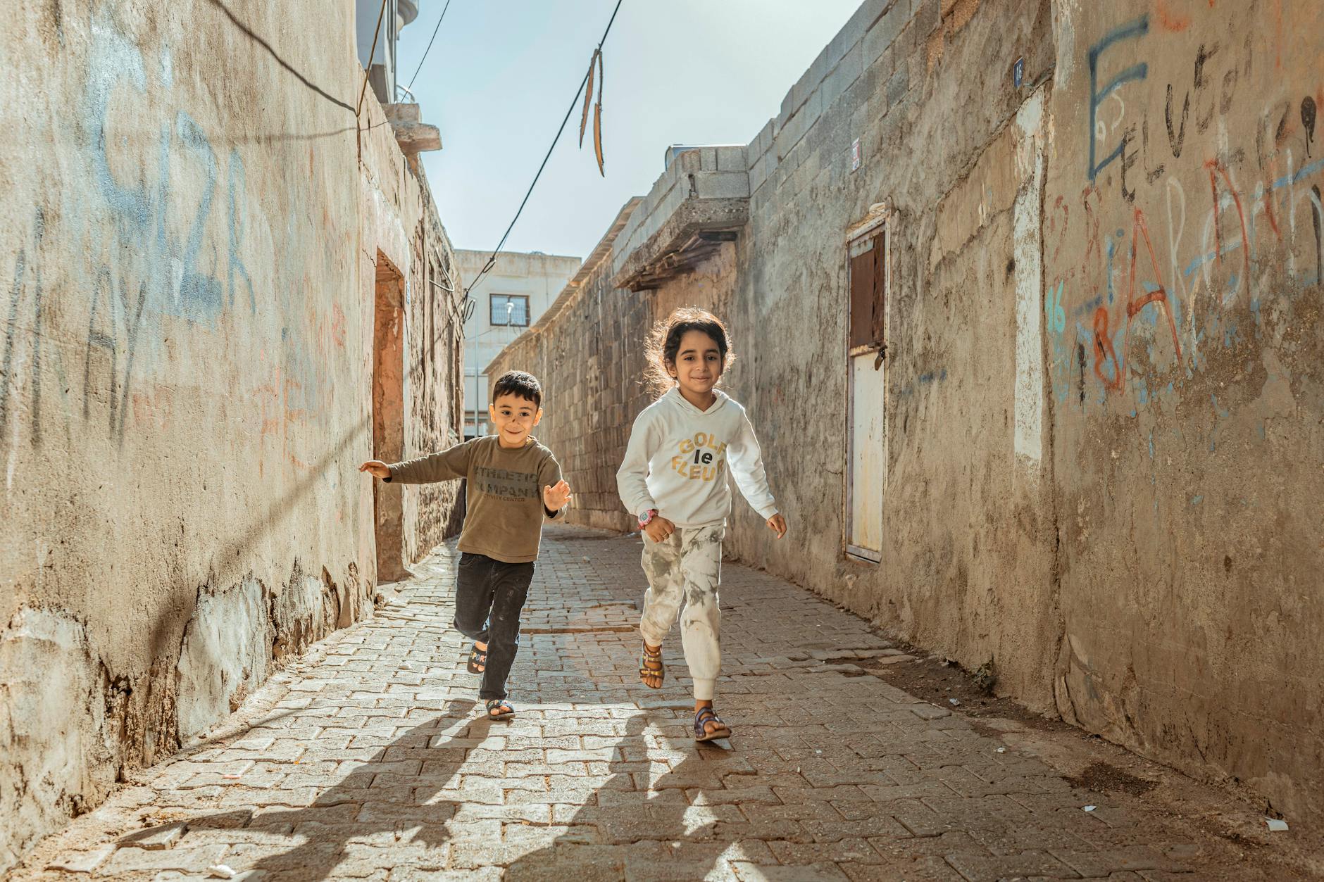 https://www.pexels.com/photo/children-running-through-street-past-abandoned-building-27697055/